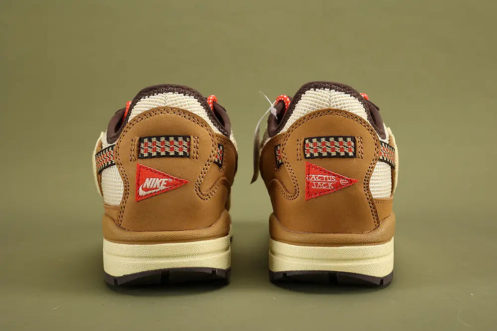 Air Max 1 Cactus Jack Wheat Lemon Drop DO9392-701 - Full Outsole View on Olive Background Showing Dark Brown Baroque Brown Rubber Outsole Square-Block and Circular Traction Pattern and White CACTUS CORPORATION Text at Outsole Heel
