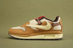 Air Max 1 Cactus Jack Wheat Lemon Drop DO9392-701 - Heel Counter Close Up on Olive Background Showing Red Triangular Pennant Flag Badge with White Swoosh Logo Diamond-Pattern Woven Ribbon Pull Tab Dark Brown Baroque Brown Suede Ankle Collar and Red Textile Collar Lining