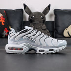 Air Max Plus TN Wolf Grey 2018 - Pair with Outsole Displayed Showing Grey Black Tread and Red Accent Dots with Pikachu on Sofa