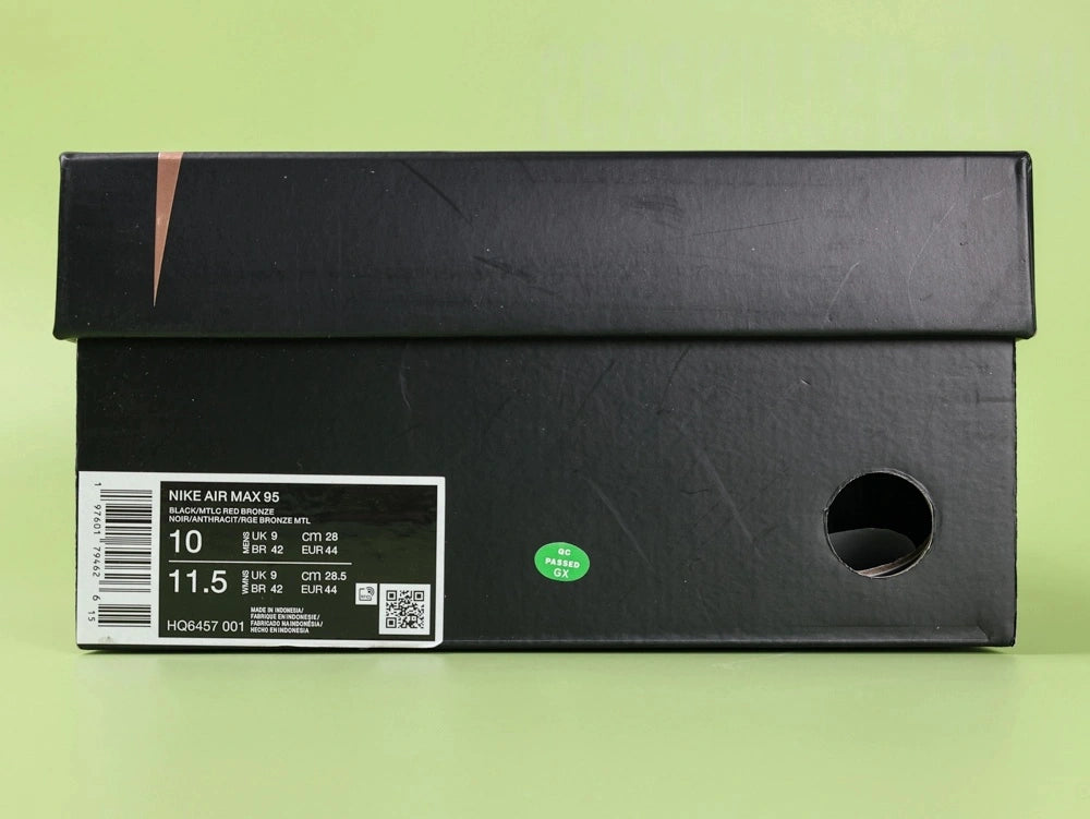 Central Cee x Air Max 95 Black and Gold - Heel Close Up Showing Central Cee Metal Charm on Ball Chain and Copper Nike Air Heel Counter on Green Background
