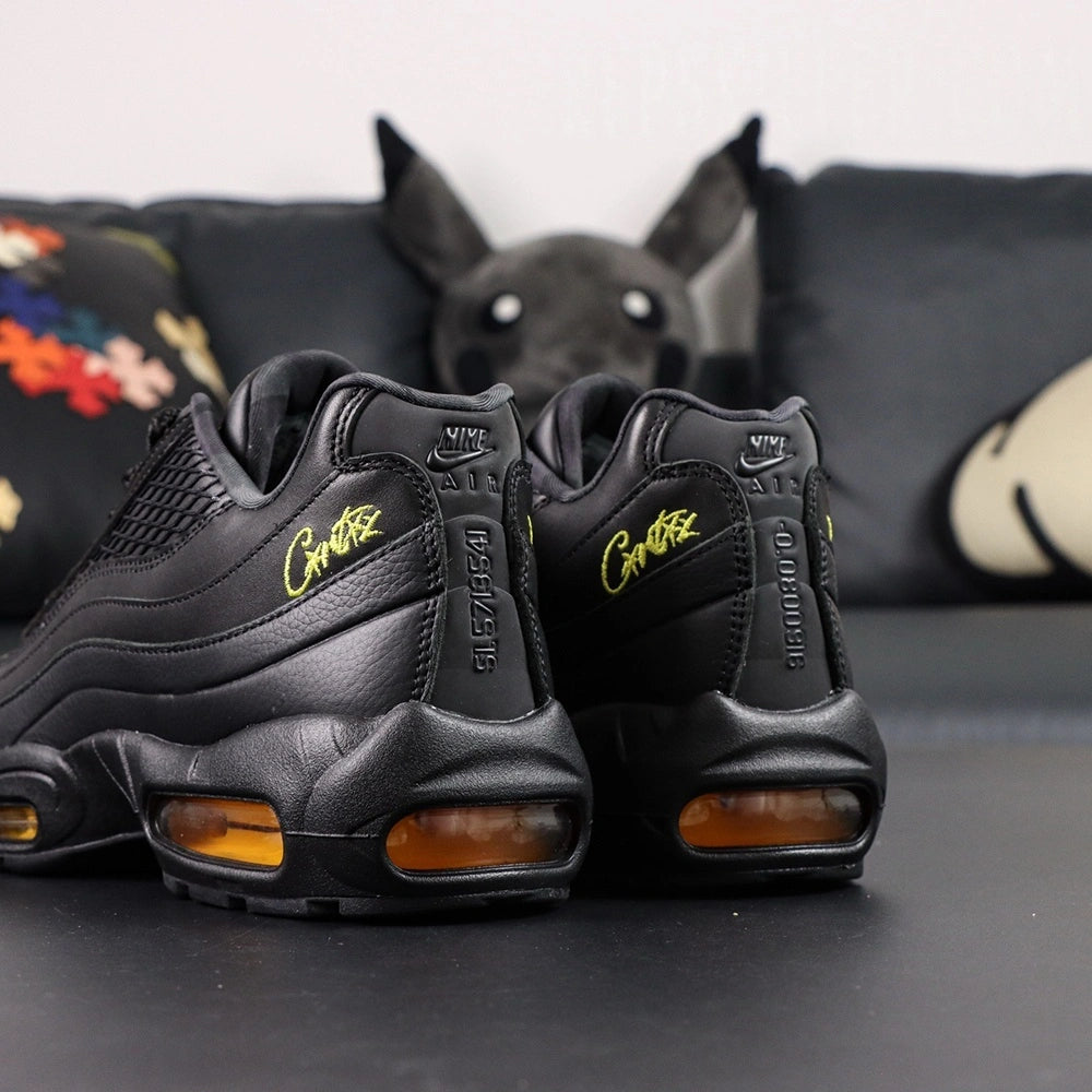 Corteiz x Air Max 95 SP Honey Blacks - Tongue Close Up Showing Oval Corteiz Alcatraz Badge in Gold on Black and Gold Nike Air Text on Dark Background