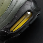 Corteiz x Air Max 95 SP Gutta Green - Lateral Side View with Pikachu on Sofa Showing Full Army Green Leather Upper Volt Swoosh and Amber Air Units