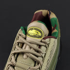 Corteiz x Air Max 95 SP Gutta Green - Toe Box Close Up Showing Volt CRTZ Monogram Logo Embroidery on Dark Olive Leather and Khaki Diamond Quilted Mesh Panel on Dark Background