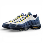 Eric Koston x Nike SB x Air Max 95 Obsidian Speed Yellow 2025 - Lateral Side View with Pikachu on Sofa Showing Full Navy Suede Upper White Terry Cloth Toe Box and Volt Swoosh