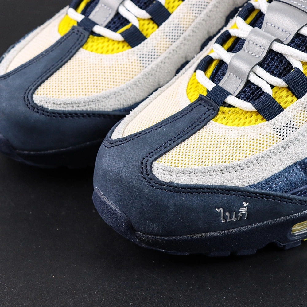 Eric Koston x Nike SB x Air Max 95 Obsidian Speed Yellow 2025 - Heel Pair Three Quarter Rear View with Pikachu on Sofa Showing Navy Suede Heel Counter and Amber Air Units