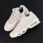 Levis x Air Max 95 OG Light Orewood Brown 2025 - Tongue Top Down Close Up on Dark Background Showing Oval Airmax Badge in Cream on Ecru and Levis Red Tab Label with Asymmetric Red Insole Levi's Left Nike Right