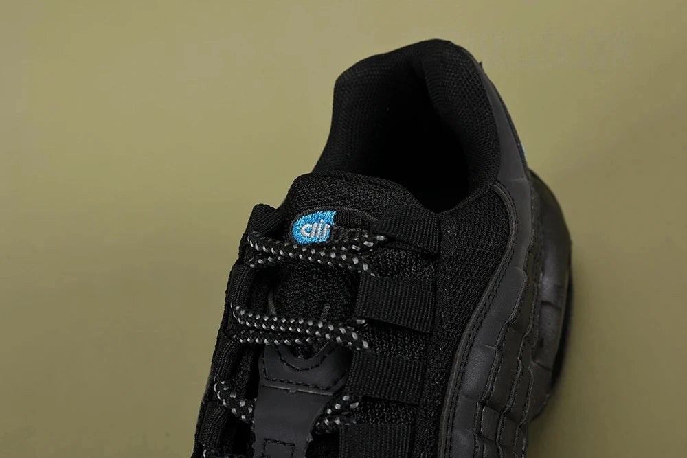 Nike Air Max 95 TT Black Laser Blue DZ4511-001 - Outsole View on Olive Background Showing Black Waffle Tread Rubber Outsole and Laser Blue Nike Swoosh Insole Visible Through Heel Air Unit