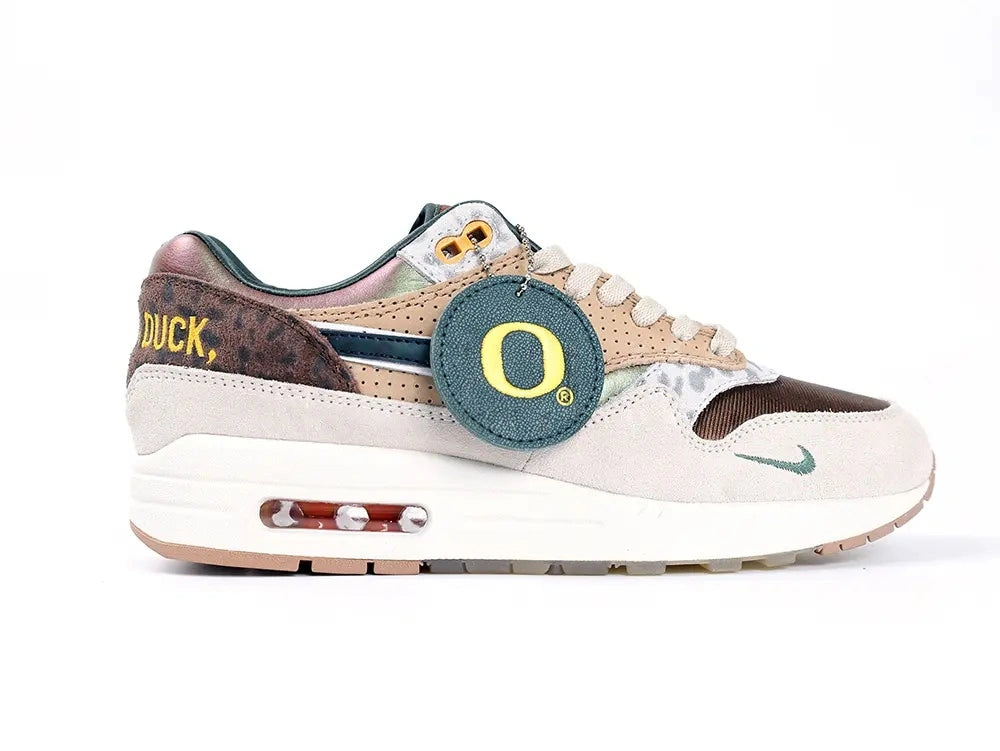 Air Max 1 87 Premium PE University of Oregon - Heel Three Quarter View on White Background Showing Yellow Once A Duck Embroidered Motto on Dark Brown Leopard Panel Iridescent Bronze Copper Heel Counter and Oregon O Hang Tag