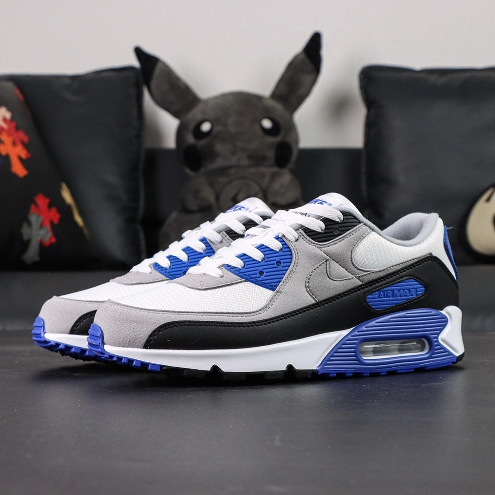 Air Max 90 Hyper Royal 2020 - Lateral Side View with Pikachu on Sofa Showing Full Upper Construction Grey Suede Swoosh Hyper Royal Blue Rear Panel and Air Max Blue Midsole Text