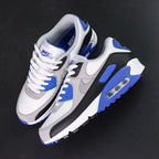 Air Max 90 Hyper Royal 2020 - Pair Lateral View with Pikachu on Sofa Showing Outsole Split Black Rubber Forefoot Waffle Tread and Hyper Royal Blue Rubber Heel Outsole