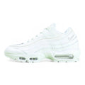 Air Max 95 Essential White Grey Fog - Lateral Heel Three Quarter View on Green Background Showing Full White Leather Upper Tonal White Spine Overlays Silver Grey Embroidered Swoosh and Translucent Clear Heel Air Unit