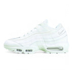 Air Max 95 Essential White Grey Fog - Lateral Heel Three Quarter View on Green Background Showing Full White Leather Upper Tonal White Spine Overlays Silver Grey Embroidered Swoosh and Translucent Clear Heel Air Unit