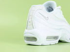 Air Max 95 Essential White Grey Fog - Lateral Spine Swoosh Close Up on Green Background Showing Silver Grey Embroidered Mini Swoosh on White Leather Spine Panel
