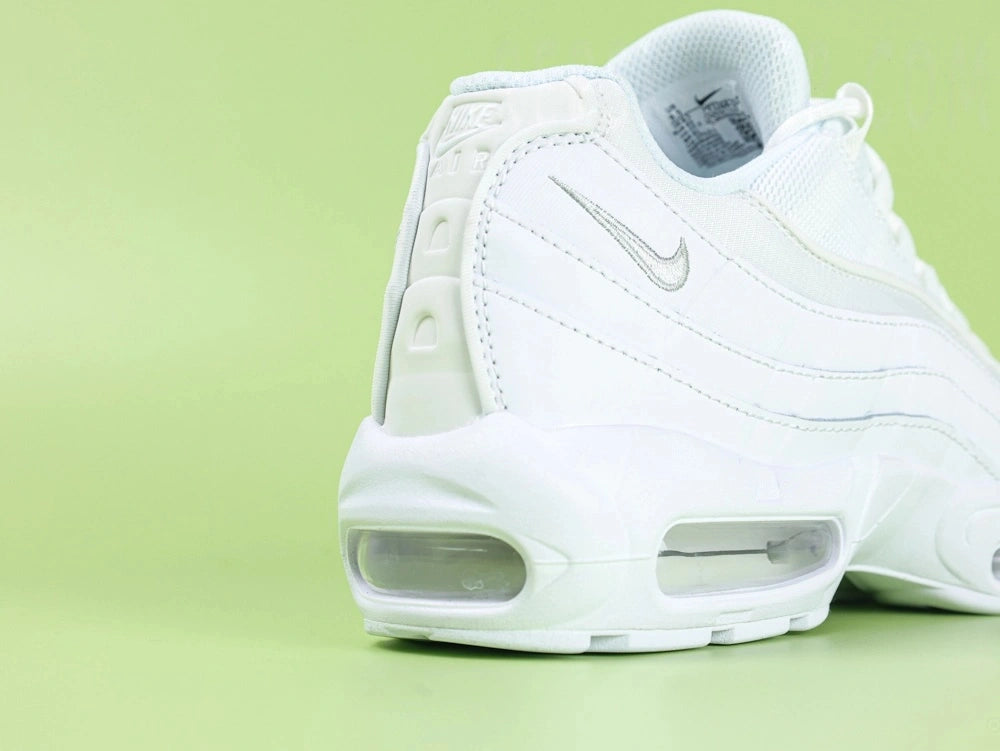 Air Max 95 Essential White Grey Fog - Lateral Spine Swoosh Close Up on Green Background Showing Silver Grey Embroidered Mini Swoosh on White Leather Spine Panel