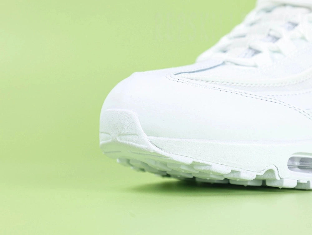 Air Max 95 Essential White Grey Fog - Heel Rear Angled View on Green Background Showing Full White Leather Heel Counter Tonal White Panel and Translucent Clear Heel Air Unit