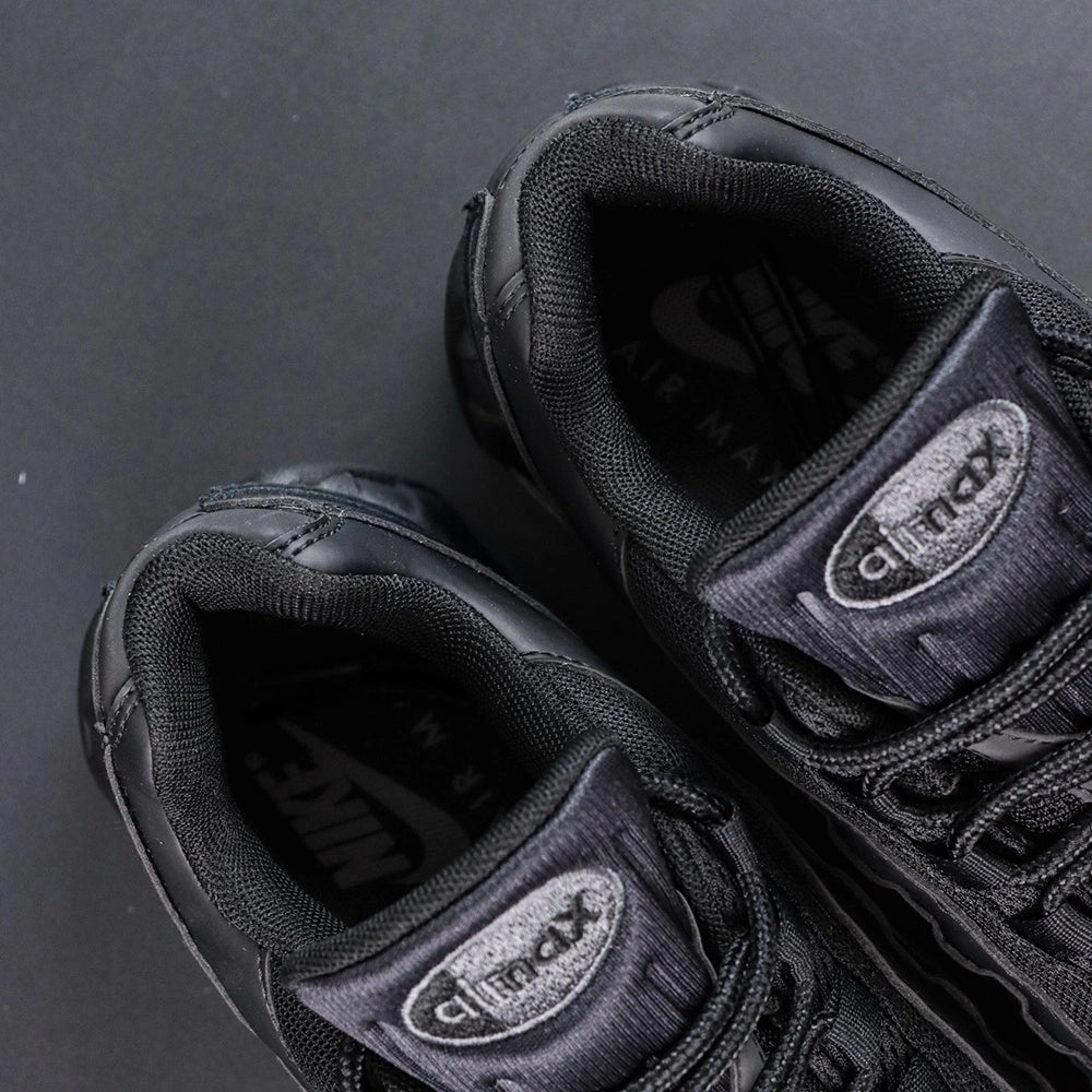 Air Max 95 OG Black Anthracite 2025 - Pair Lateral and Outsole View with Pikachu on Sofa Showing Full Black AM95 Square Block Waffle Tread Outsole and Translucent Smoke Blue Heel Air Unit