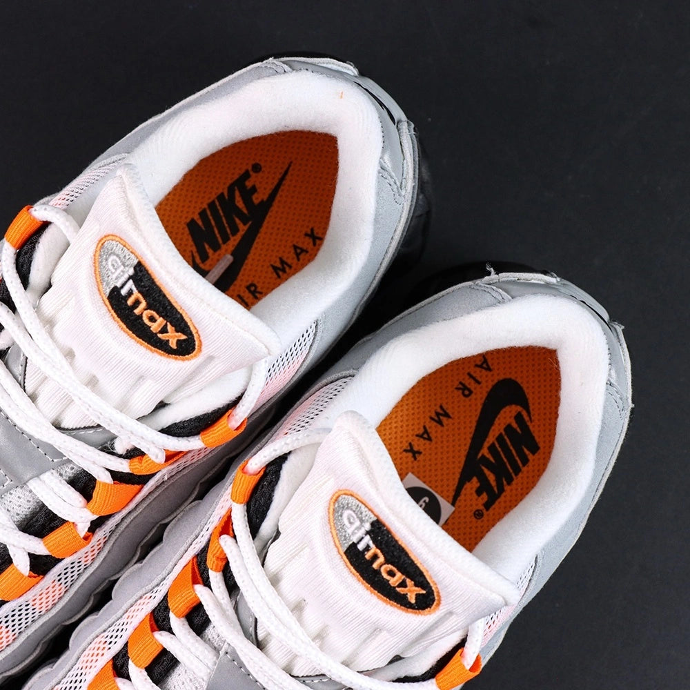 Air Max 95 OG Bright Mandarin 2.0 2025 - Pair Heel Three Quarter Rear View with Pikachu on Sofa Showing Grey Suede Heel Badge Orange Swoosh Orange Translucent Air Units and Black Midsole