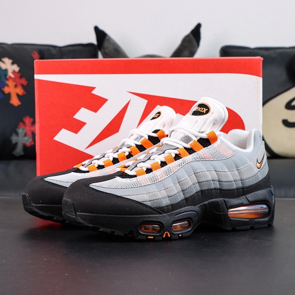 Air Max 95 OG Bright Mandarin 2.0 2025 - Pair Toe Box Forefoot Close Up on Dark Background Showing Black Suede Mudguard White Mesh Quarter Panel Light Grey Forefoot Spine and Bright Mandarin Orange Lace Loops