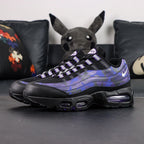 Air Max 95 OG Purple Camo 2025 - Pair Heel Rear View with Pikachu on Sofa Showing Silver Grey Lower Heel Badge with Black Nike Air Text White Swoosh and Purple Camo Upper Heel Panel with Purple Translucent Heel Air Units