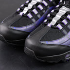 Air Max 95 OG Purple Camo 2025 - Pair Heel Rear View with Pikachu on Sofa Showing Silver Grey Lower Heel Badge Black Nike Air Text White Swoosh Purple Camo Upper Heel Panel and Purple Translucent Heel Air Units