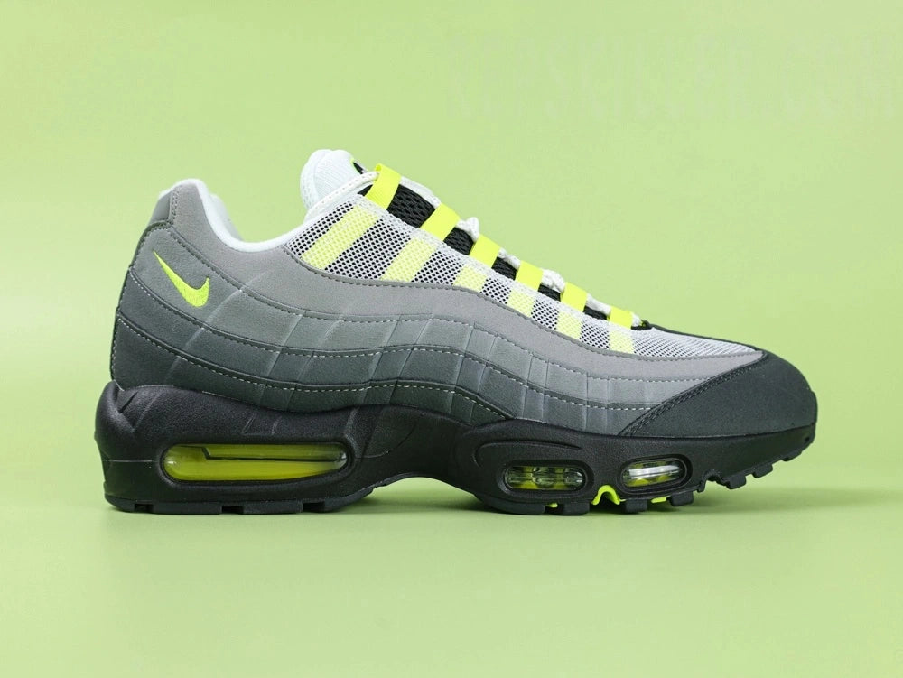 Air Max 95 OG Neon CT1689-001 - Toe Box Forefoot Close Up on Green Background Showing Black Suede Mudguard White Mesh Quarter Panel Light Grey Suede Forefoot Spine and Neon Yellow Lace Loops