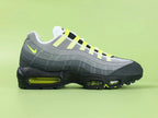 Air Max 95 OG Neon CT1689-001 - Toe Box Forefoot Close Up on Green Background Showing Black Suede Mudguard White Mesh Quarter Panel Light Grey Suede Forefoot Spine and Neon Yellow Lace Loops