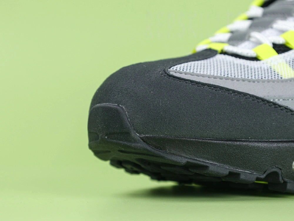 Air Max 95 OG Neon CT1689-001 - Lateral Spine Swoosh Close Up on Green Background Showing Neon Yellow Volt Embroidered Mini Swoosh on Dark Grey Charcoal Suede Spine Panel
