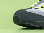 Air Max 95 OG Neon CT1689-001 - Lateral Spine Swoosh Close Up on Green Background Showing Neon Yellow Volt Embroidered Mini Swoosh on Dark Grey Charcoal Suede Spine Panel