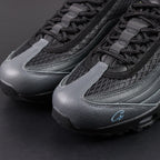 Air Max 95 SP Corteiz Aegean Storm - Pair Top Down Tongue and Collar Close Up on Dark Background Showing Black Leather Tongue with Silver Grey Airmax Badge and Olive Green Brown Black Military Camo Print Collar Lining