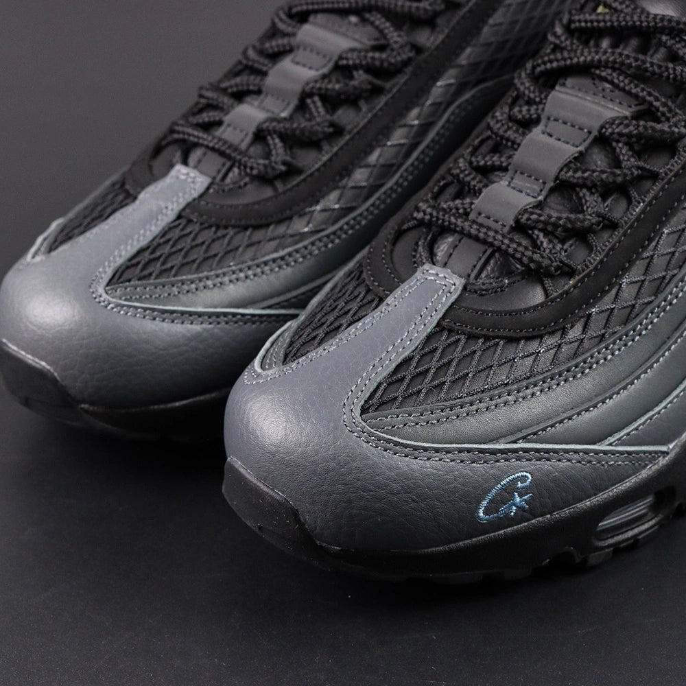 Air Max 95 SP Corteiz Aegean Storm - Pair Top Down Tongue and Collar Close Up on Dark Background Showing Black Leather Tongue with Silver Grey Airmax Badge and Olive Green Brown Black Military Camo Print Collar Lining