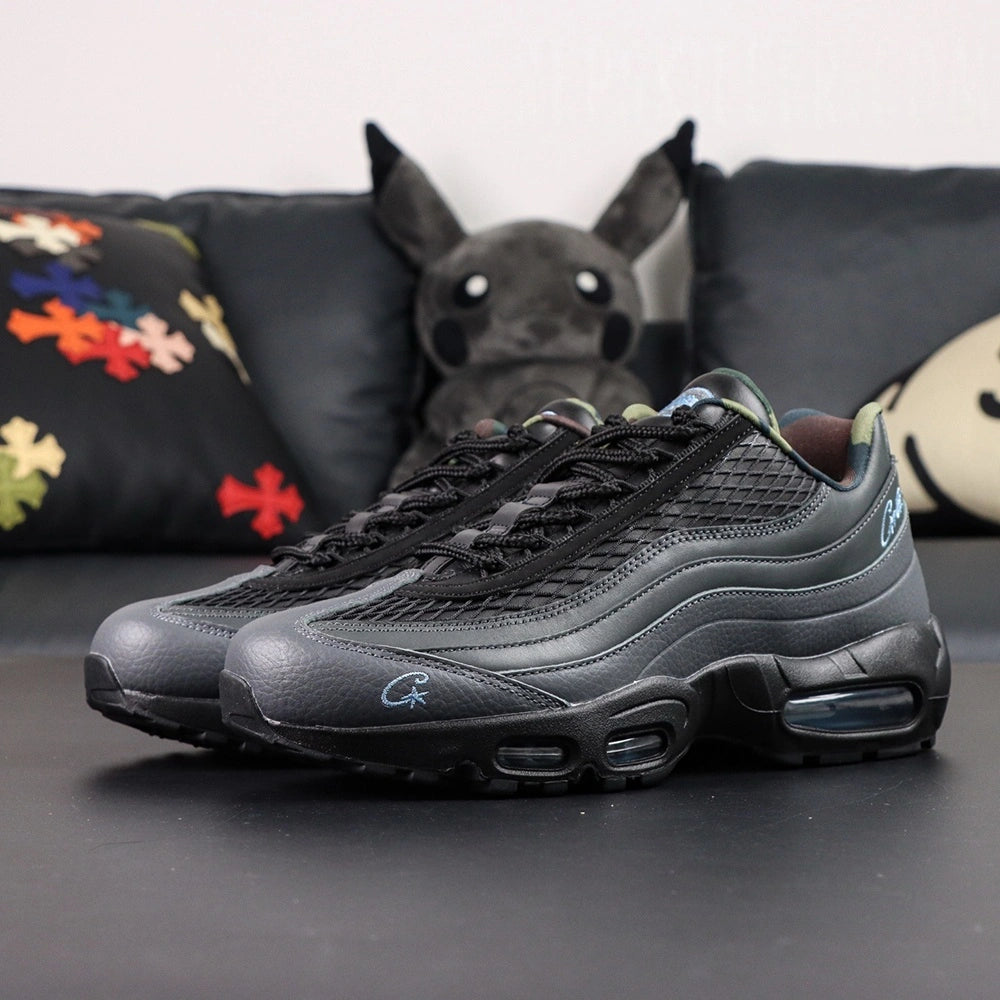 Air Max 95 SP Corteiz Aegean Storm - Pair Heel Rear View with Pikachu on Sofa Showing Black Pebbled Leather Heel Counter with Black Nike Air Text White Corteiz Cursive Script Embroidery Serialised Heel Number and Steel Blue Translucent Heel Air Units
