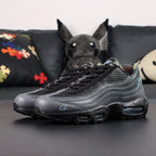 Air Max 95 SP Corteiz Aegean Storm - Pair Heel Rear View with Pikachu on Sofa Showing Black Pebbled Leather Heel Counter with Black Nike Air Text White Corteiz Cursive Script Embroidery Serialised Heel Number and Steel Blue Translucent Heel Air Units