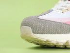 Air Max 95 TT Anatomy of Air - Heel Spine Swoosh Close Up on Green Background Showing Rose Pink Leather Spine Panel with Cream Off White Embroidered Mini Swoosh and Bright Red Lower Spine Panel with Red Contrast Stitching
