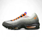 Air Max 95 TT Greedy - Lateral Spine Swoosh Close Up on Green Background Showing Medium Grey Suede Spine Panel with Orange Embroidered Mini Swoosh and Dark Charcoal Lower Spine Panel with Grey Contrast Stitching