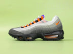Air Max 95 TT Greedy - Single Lateral Full Side View on Green Background Showing Volt Neon Colourway Dark Charcoal Suede Toe Box White Mesh Base Grey Gradient Spine Volt Mini Swoosh Volt Lace Loops and Volt Translucent Air Units