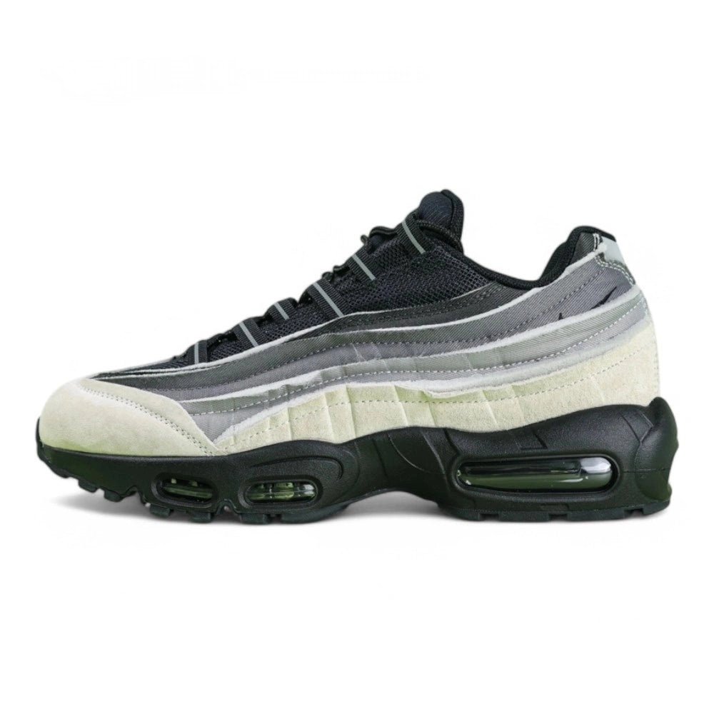 Air Max 95 x Comme des Garçons Charcoal - Heel Rear Three-Quarter View on Green Background Showing Silver Hard Plastic AM95 Heel Stabiliser with AIR Text Grey Gradient Suede Spine and Black Translucent Air Unit