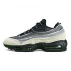 Air Max 95 x Comme des Garçons Charcoal - Heel Rear Three-Quarter View on Green Background Showing Silver Hard Plastic AM95 Heel Stabiliser with AIR Text Grey Gradient Suede Spine and Black Translucent Air Unit