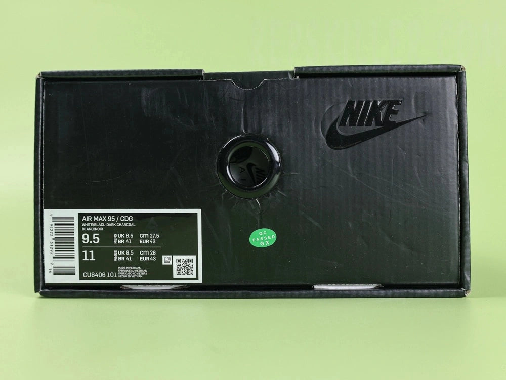 Air Max 95 x Comme des Garçons Charcoal - Toe Box Close Up on Green Background Showing Cream Off-White Suede Mudguard Black Mesh Quarter Panel and Reflective Grey Lace Loops