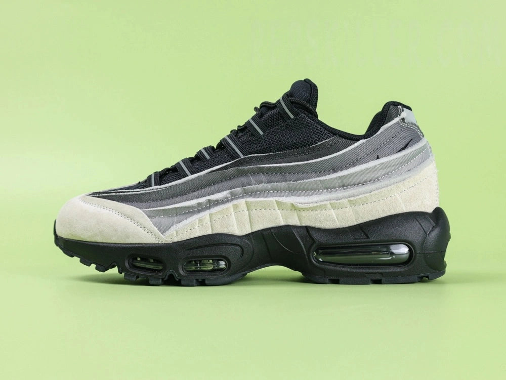 Air Max 95 x Comme des Garçons Charcoal - Outsole View on Green Background Showing Full Black AM95 Square Block Waffle Tread with Central Translucent Window Revealing Black and White Striped Insole Graphic