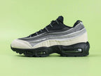 Air Max 95 x Comme des Garçons Charcoal - Outsole View on Green Background Showing Full Black AM95 Square Block Waffle Tread with Central Translucent Window Revealing Black and White Striped Insole Graphic