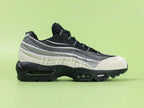 Air Max 95 x Comme des Garçons Charcoal - Toe Box Top Down View on Green Background Showing Cream Suede Mudguard Black Mesh Upper and Reflective Grey Lace Dubrae Details