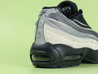 Air Max 95 x Comme des Garçons Charcoal - Tongue Close Up on Green Background Showing Black Ribbed Fabric Tongue with Tonal Black Embroidered Oval Airmax Badge