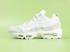 Air Max 95 x Comme des Garçons White - Outsole View on Green Background Showing Full White AM95 Square Block Waffle Tread with Central Translucent Window Revealing Black and White Striped Insole Graphic