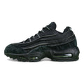 Air Max 95 x Comme des Garçons Black - Heel Rear Three-Quarter View on Green Background Showing Silver Hard Plastic AM95 Heel Stabiliser with AIR Text Black Suede Upper and Black Translucent Air Unit