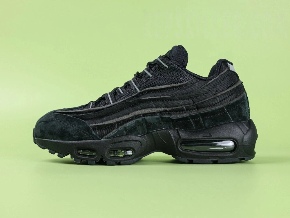 Air Max 95 x Comme des Garçons Black - Outsole View on Green Background Showing Full Black AM95 Square Block Waffle Tread with Central Translucent Window Revealing Black and White Striped Insole Graphic