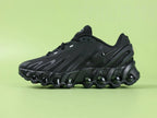 Air Max Dn8 All Black - Outsole View on Green Background Showing Full Black Rubber Outsole with Red Circular Traction Studs and Gold Circular Dn Badge at Midfoot