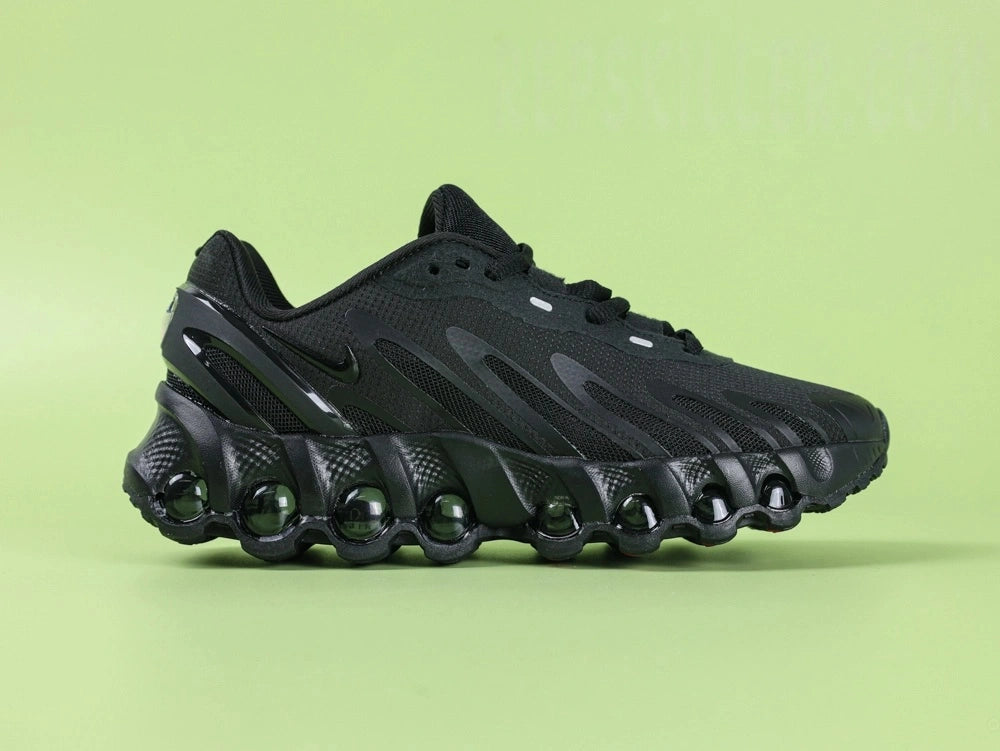 Air Max Dn8 All Black - Toe Box Top Down View on Green Background Showing Black Engineered Mesh Upper Black TPU Overlays and Tonal Black Swoosh on Lace Area