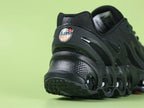 Air Max Dn8 All Black - Tongue Close Up on Green Background Showing Tonal Black Rubber Oval AIRMAX Badge Debossed on Black Mesh Tongue