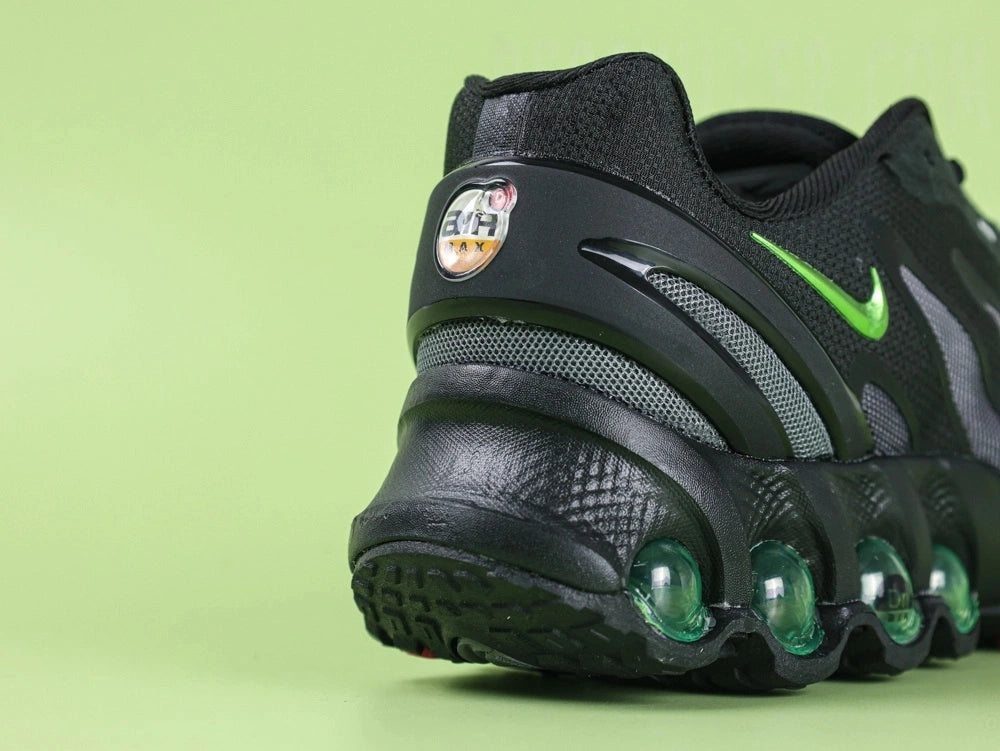 Air Max Dn8 Black Volt - Swoosh Close Up on Green Background Showing Metallic Volt Green Chrome Mirror Finish Swoosh on Black Engineered Mesh Midfoot Panel