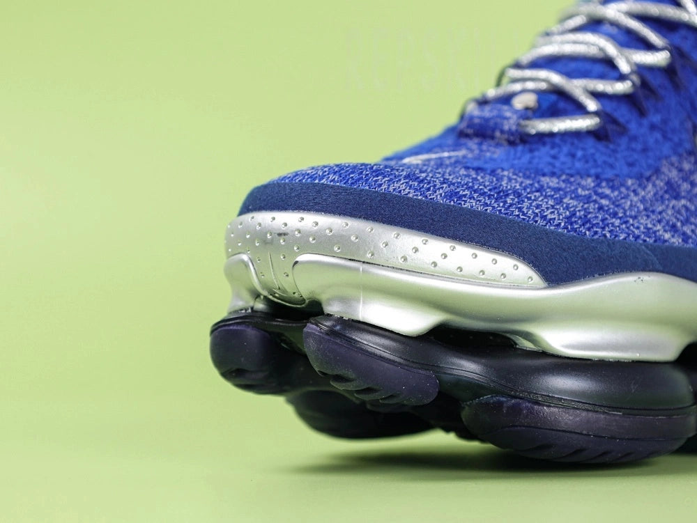 Air Max Scorpion FK Blue Fury - Swoosh Close Up on Green Background Showing Silver Metallic Thread Embroidered Mini Swoosh on Royal Blue and Navy Dual-Tone Flyknit Toe Box Panel